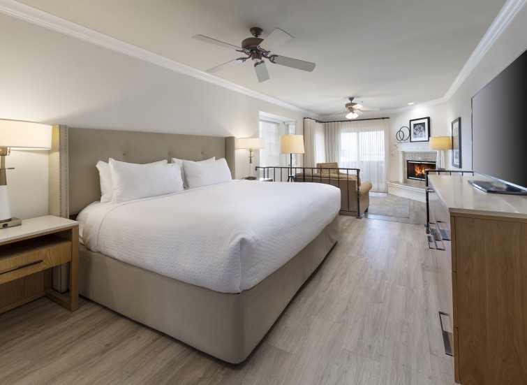 A large hotel room with a king-sized bed, fireplace, and flat screen TV