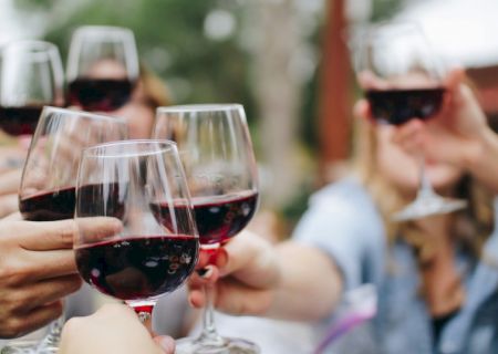 A group of people clinking wine glasses at a toast, smiling and celebrating together.